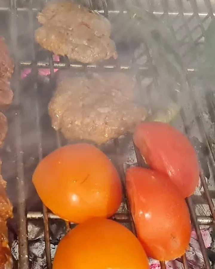 Köfte und Tomaten auf dem Grillrost über der Glut